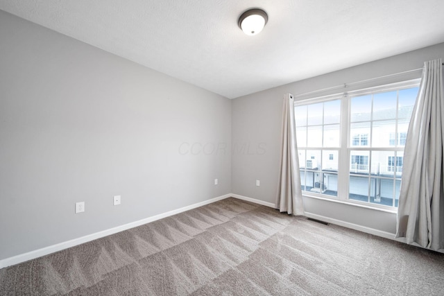 carpeted spare room featuring visible vents and baseboards