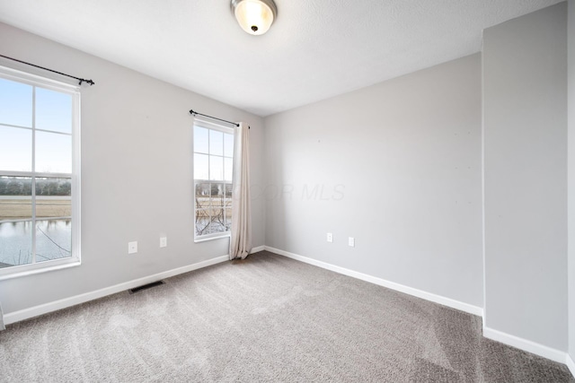 unfurnished room featuring baseboards, visible vents, and carpet flooring