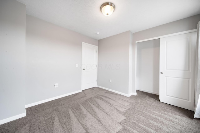 unfurnished bedroom with a closet, carpet flooring, and baseboards