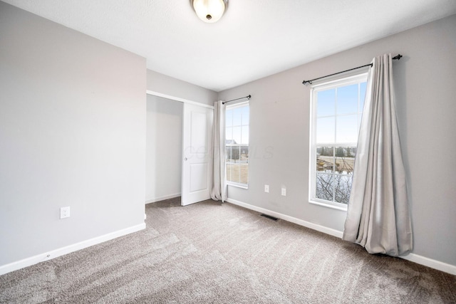 unfurnished bedroom with carpet, visible vents, baseboards, and a closet