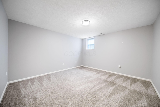 unfurnished room with a textured ceiling, baseboards, and carpet flooring