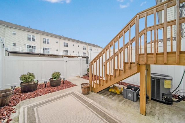 view of patio with cooling unit, a fenced backyard, and stairway