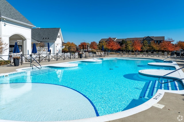 pool with a patio area and fence