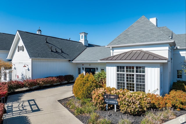 view of front of home featuring a standing seam roof, brick siding, metal roof, and a chimney