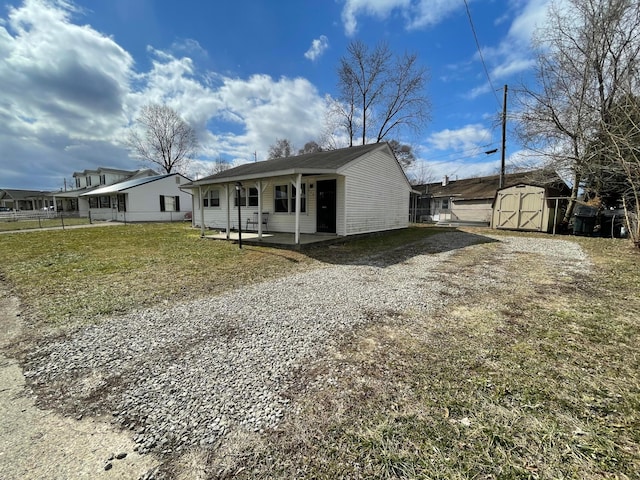 view of front of house with an outbuilding, a front yard, a patio area, fence, and a shed