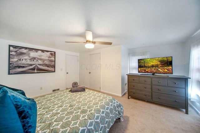 bedroom featuring light carpet, baseboards, visible vents, and ceiling fan