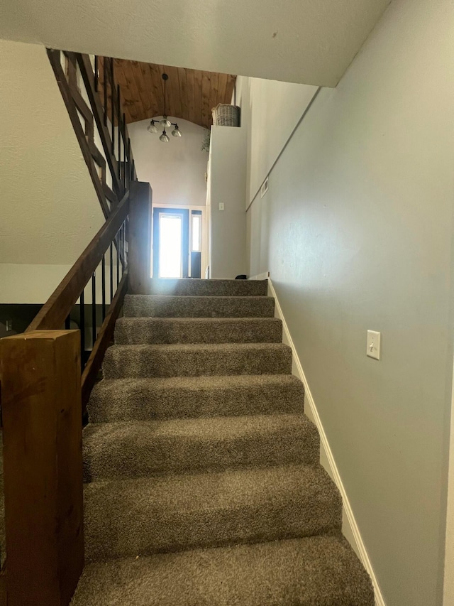 staircase with lofted ceiling, carpet, and baseboards