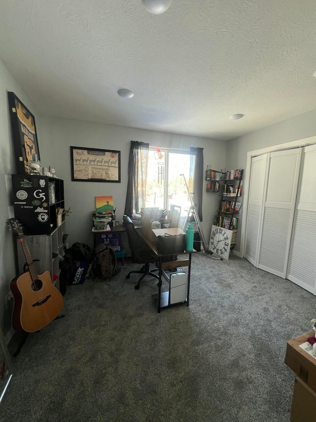 carpeted home office featuring a textured ceiling