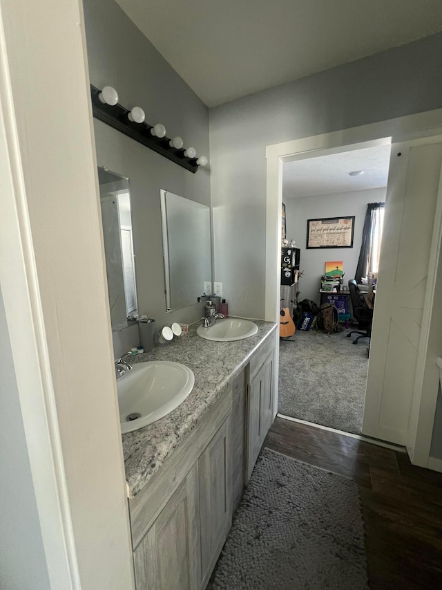 bathroom with double vanity, a sink, and wood finished floors