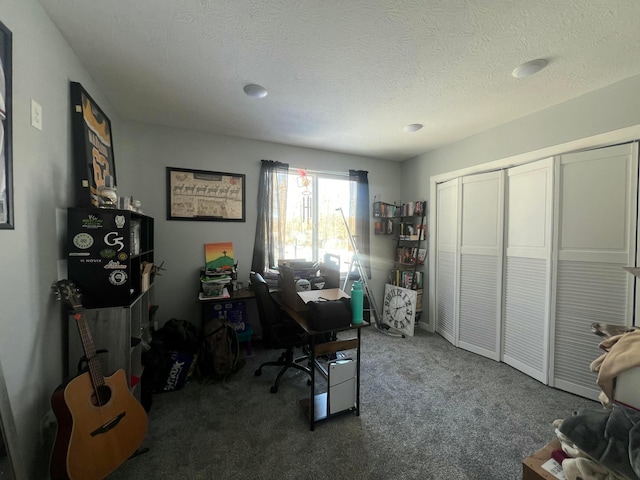 carpeted home office featuring a textured ceiling