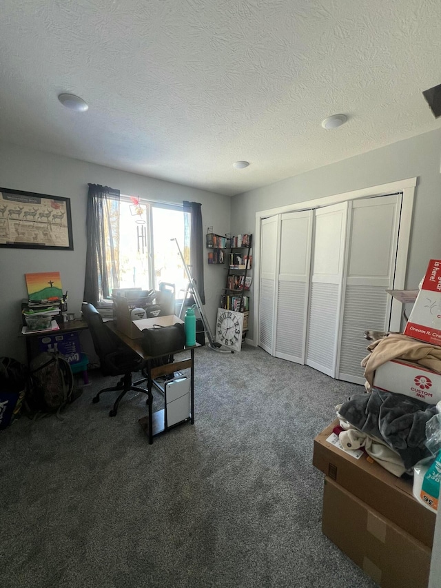 carpeted home office featuring a textured ceiling