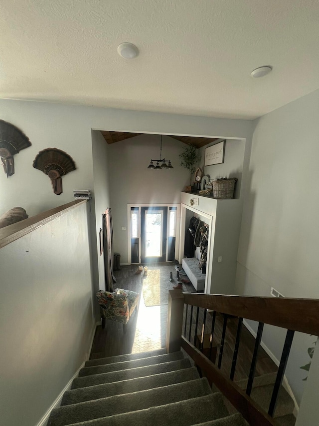 staircase with a textured ceiling, baseboards, and wood finished floors