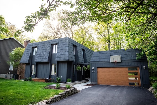 view of front facade with mansard roof, asphalt driveway, an attached garage, a front lawn, and board and batten siding