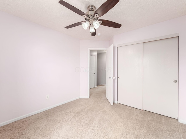 unfurnished bedroom featuring a textured ceiling, ceiling fan, a closet, and light colored carpet