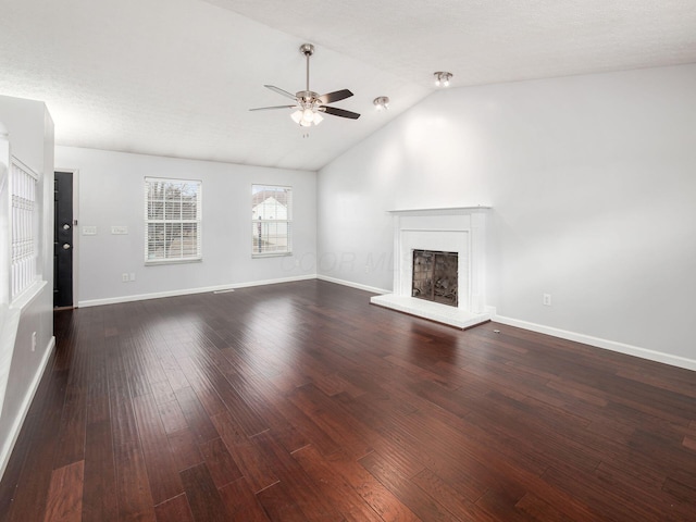 unfurnished living room with lofted ceiling, a fireplace with raised hearth, ceiling fan, wood finished floors, and baseboards