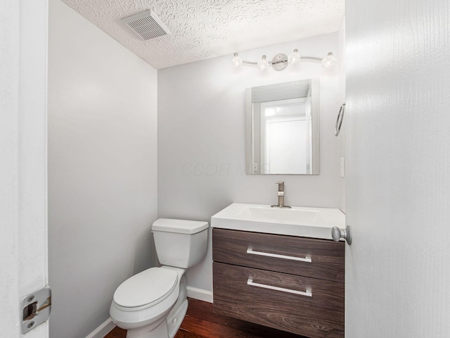 bathroom featuring visible vents, toilet, wood finished floors, a textured ceiling, and vanity