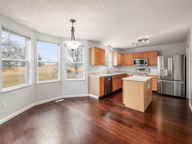 kitchen with stainless steel appliances, a sink, visible vents, light countertops, and dark wood finished floors