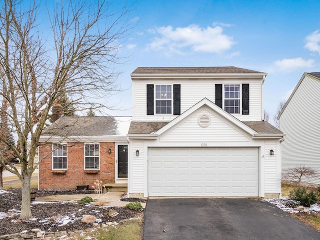 traditional-style house with a garage, a shingled roof, aphalt driveway, and brick siding