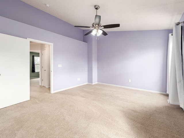 unfurnished room featuring ceiling fan, baseboards, a textured ceiling, and light colored carpet