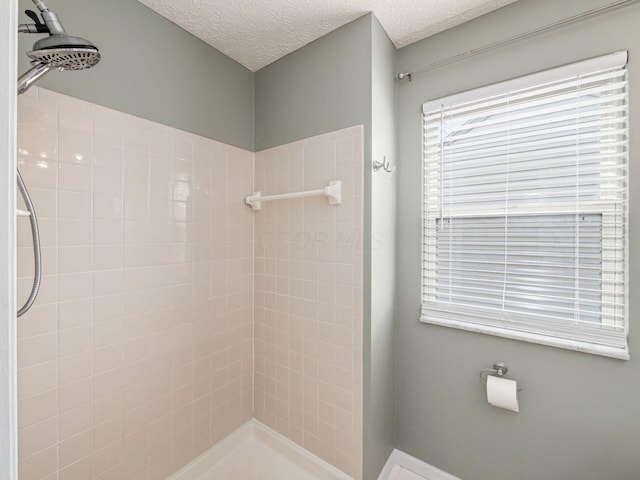 full bath featuring tiled shower and a textured ceiling