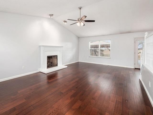 unfurnished living room featuring vaulted ceiling, baseboards, a fireplace with raised hearth, and dark wood-style flooring