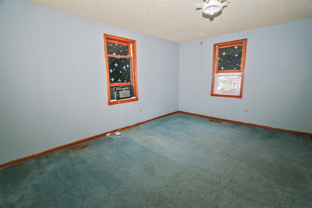 empty room with visible vents, carpet flooring, a textured ceiling, cooling unit, and baseboards