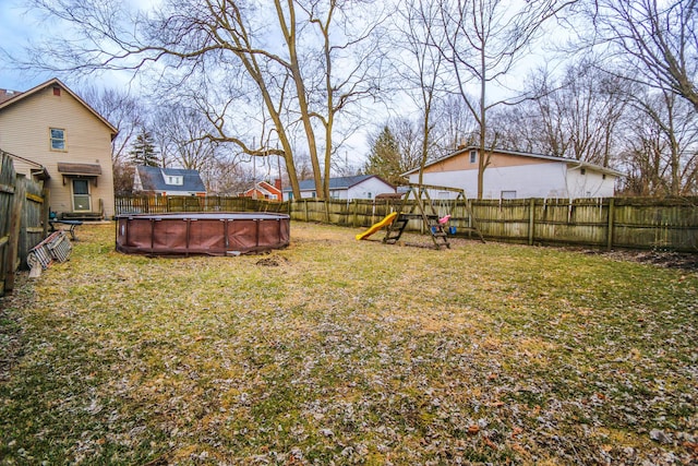 view of yard with a fenced backyard, a fenced in pool, and a playground