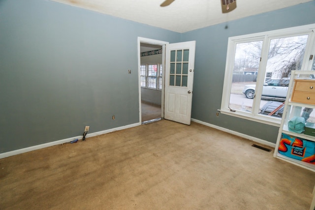 carpeted spare room with a ceiling fan, visible vents, and baseboards