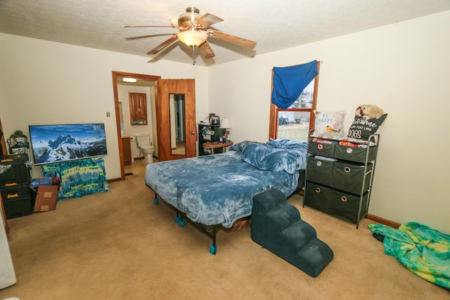 carpeted bedroom with a textured ceiling, connected bathroom, a ceiling fan, and baseboards