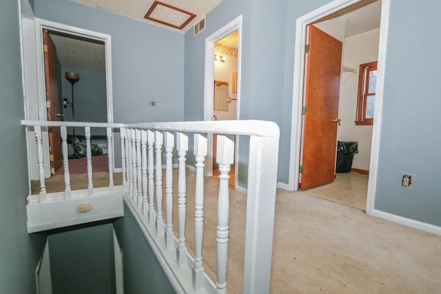 hall with carpet, baseboards, and visible vents