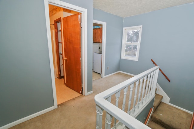 hall featuring carpet, stairs, baseboards, and a textured ceiling