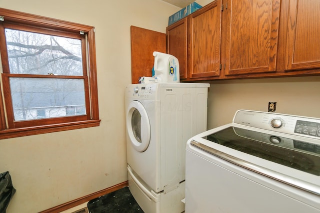 laundry room featuring washer and dryer, cabinet space, and baseboards