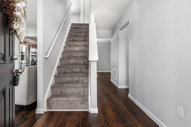 stairway with visible vents, baseboards, and wood finished floors