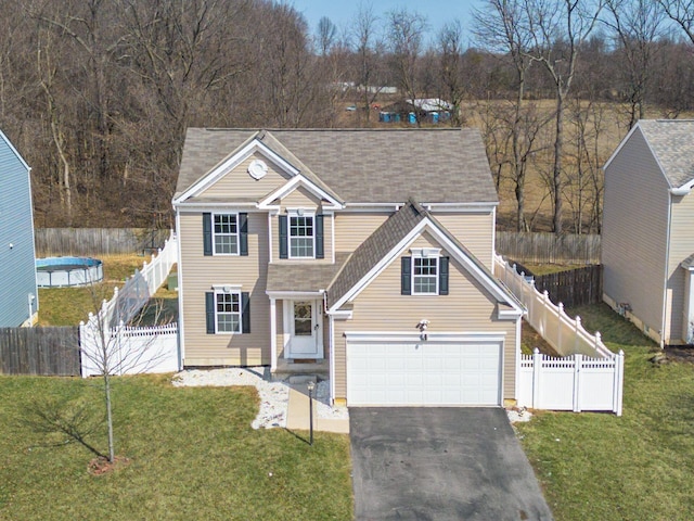 traditional-style home with aphalt driveway, a garage, fence private yard, and a front yard