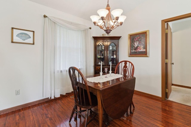 dining space with baseboards, an inviting chandelier, and wood finished floors