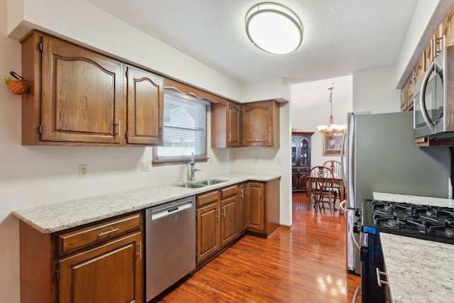 kitchen featuring appliances with stainless steel finishes, brown cabinetry, dark wood-type flooring, and a sink