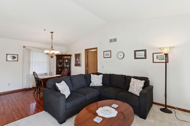 living area featuring baseboards, visible vents, vaulted ceiling, light wood-type flooring, and a chandelier