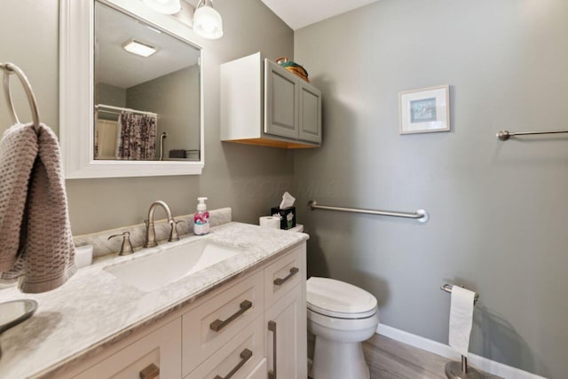 full bathroom with toilet, baseboards, wood finished floors, and vanity