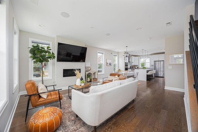 living area featuring dark wood finished floors, recessed lighting, visible vents, a glass covered fireplace, and baseboards