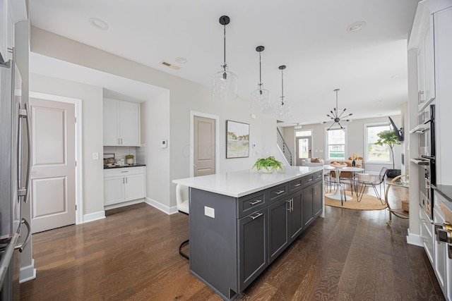 kitchen featuring dark wood-style flooring, visible vents, white cabinets, backsplash, and freestanding refrigerator