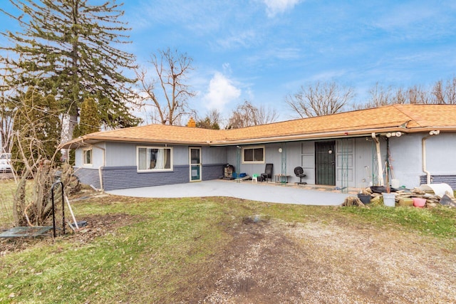 rear view of house featuring driveway, a lawn, and a patio