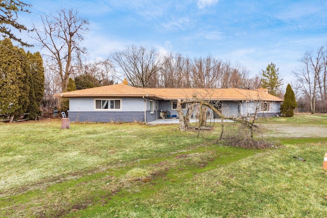 single story home featuring a front yard, brick siding, a chimney, and stucco siding