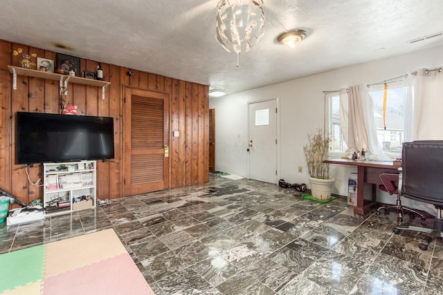 living area with visible vents, wood walls, and a textured ceiling