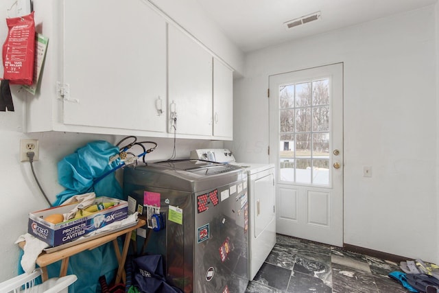 washroom featuring visible vents, cabinet space, and washing machine and clothes dryer