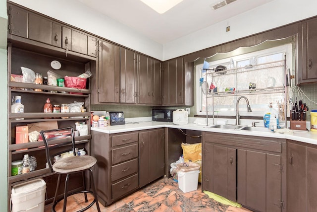 kitchen featuring visible vents, decorative backsplash, light countertops, dark brown cabinets, and a sink