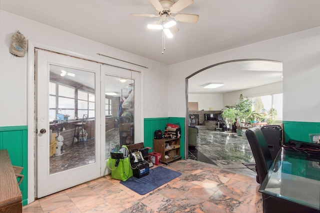 office featuring arched walkways, a ceiling fan, and wainscoting