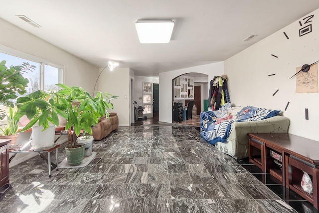 bedroom with arched walkways, marble finish floor, and visible vents