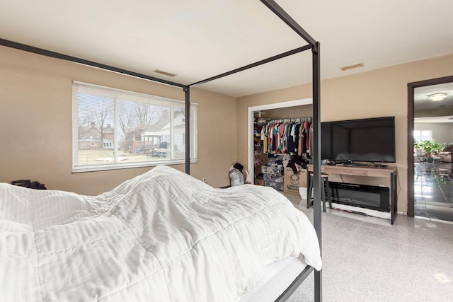 bedroom with speckled floor, multiple windows, a closet, and visible vents