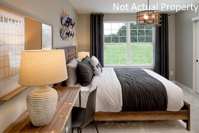 carpeted bedroom featuring baseboards and a chandelier