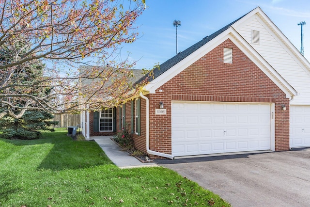 view of front of house featuring an attached garage, a front yard, aphalt driveway, and brick siding